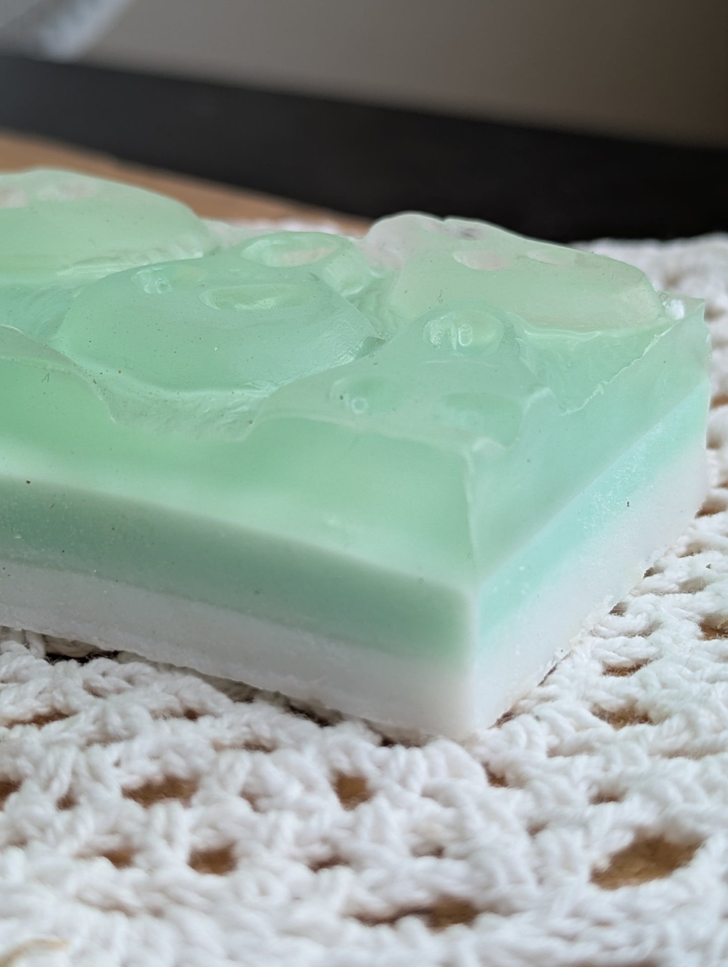 Green and white layered soap bar on a textured white surface