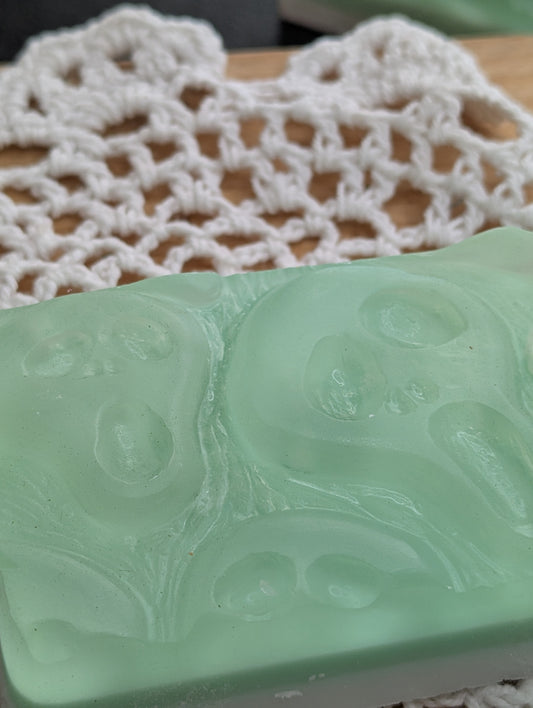 Green soap bar with embossed design on a white lace doily