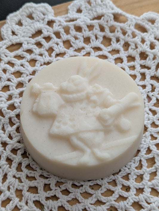 White shampoo soap bar with a design of a Rabbit playing a trumpet akin to the Alice in Wonderland classic, on a white lace doily