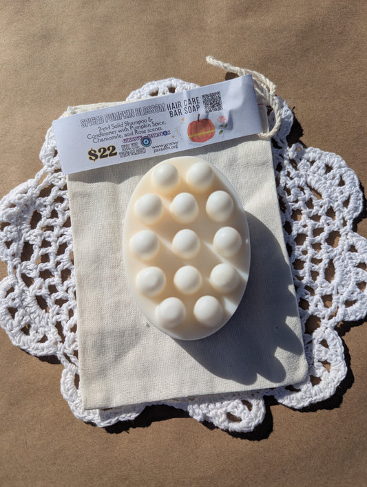 White oval hair bar soap with massaging side on a cloth with a price tag on a brown background
