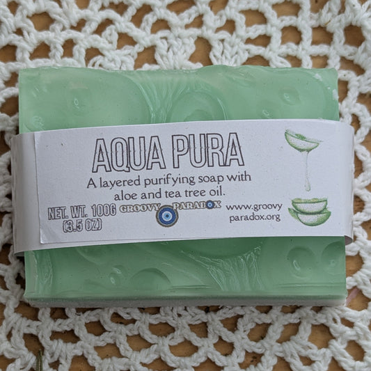 Green soap bar with 'Aqua Pura' label on a white textured surface
