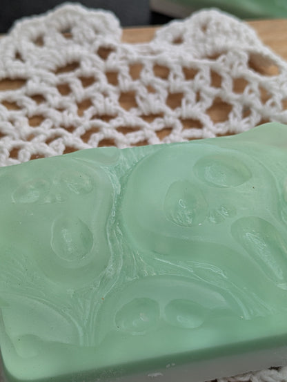 Green soap bar with embossed design on a white lace doily