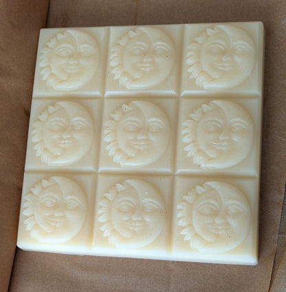 Block of 9 facial soap bars with sun and moon face designs on a brown parchment paper background