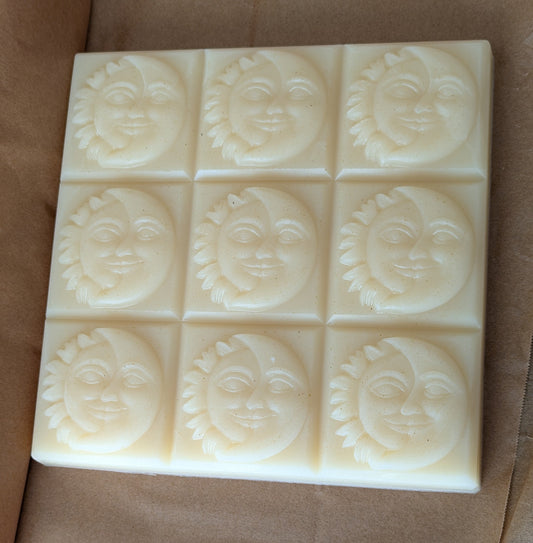 Block of 9 facial soap bars with sun and moon face designs on a brown parchment paper background