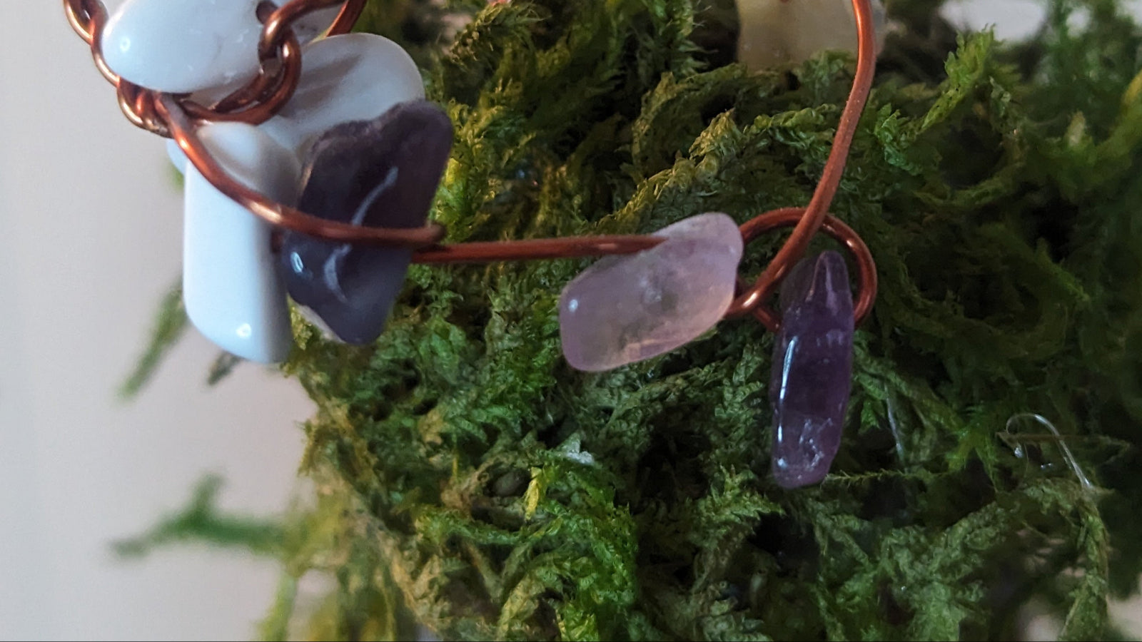 A decorative Golden Aura Fairy Amplifier made from upcycled bottles with gold paint, adorned with crystals, rice, and herbs, placed in a garden setting.